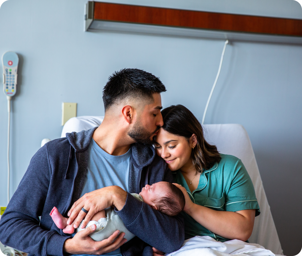 New parents embracing newborn in hospital